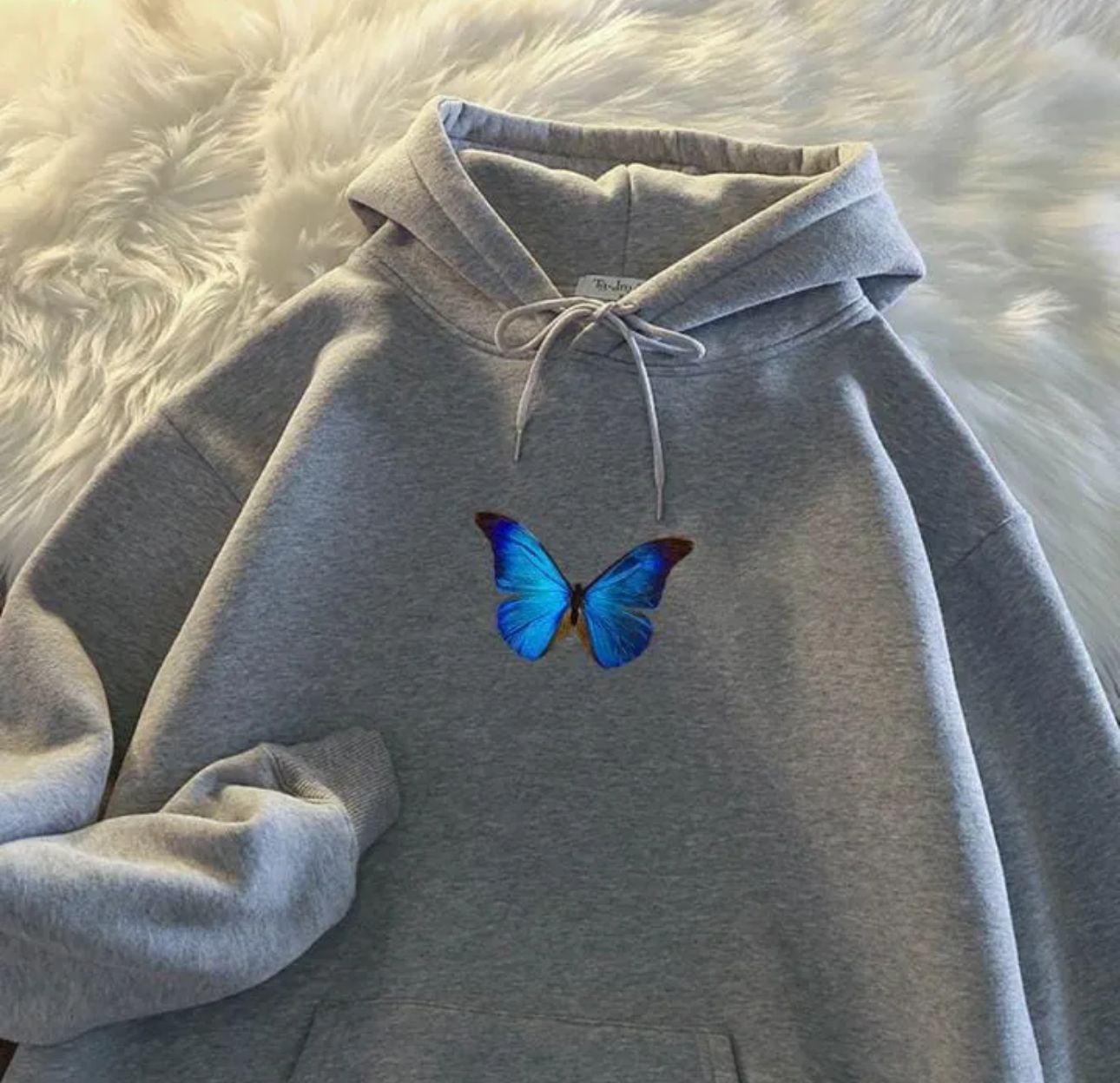 Fleece pullover hoodie with a small blue and cyan butterfly chest graphic, kangaroo pocket, and drawstring hood.